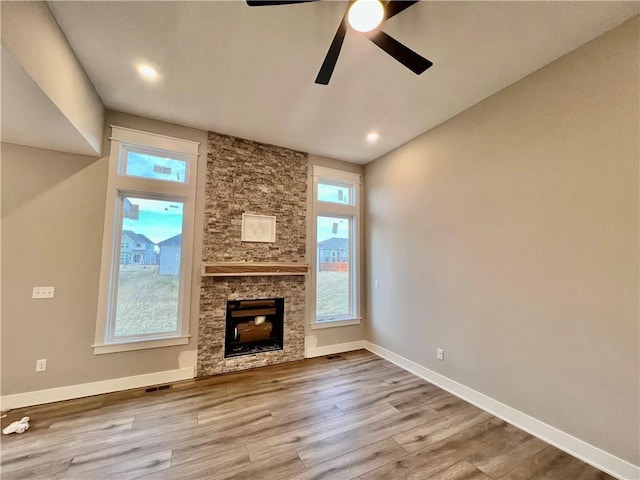 unfurnished living room with visible vents, a ceiling fan, wood finished floors, a fireplace, and baseboards