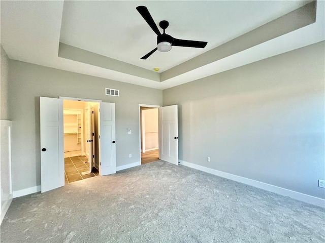 unfurnished bedroom with visible vents, baseboards, and a tray ceiling