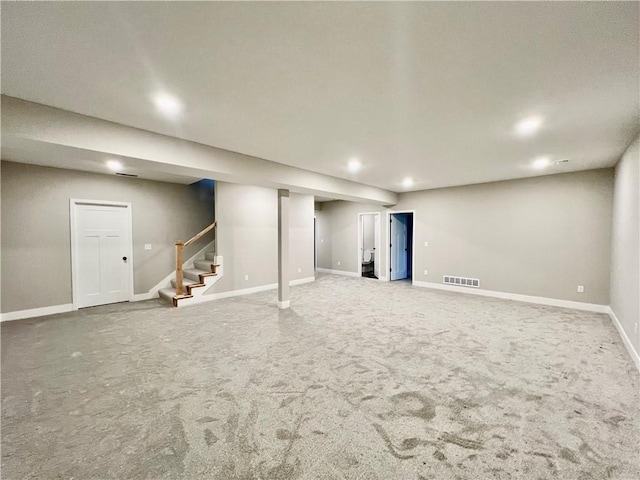 finished basement featuring visible vents, baseboards, carpet floors, and stairs