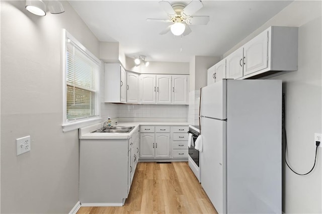 kitchen featuring sink, backsplash, white cabinetry, light wood-type flooring, and white appliances