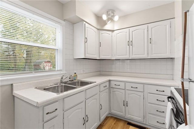 kitchen with tasteful backsplash, sink, white cabinets, and white electric range oven