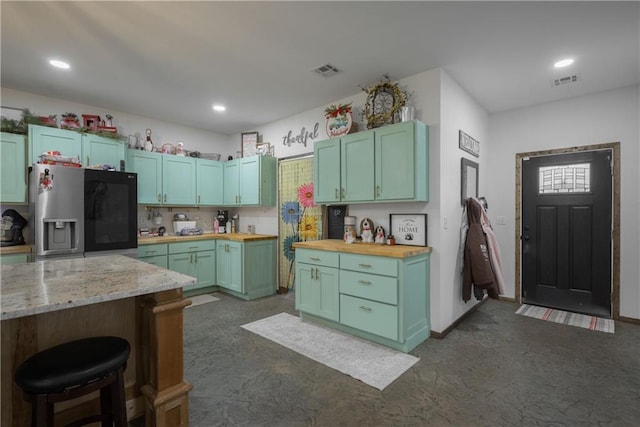 5528 Lostine Rd, Galena, KS 66739 - kitchen with a breakfast bar, stainless steel refrigerator with ice dispenser, butcher block counters, and visible vents