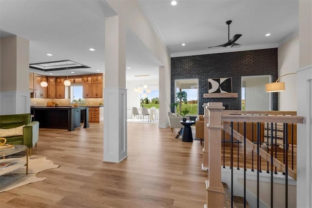 living room with wine cooler, crown molding, light hardwood / wood-style floors, brick wall, and ceiling fan with notable chandelier