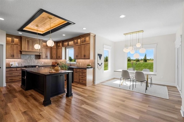 kitchen with a center island, pendant lighting, backsplash, and a tray ceiling