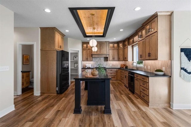 kitchen featuring sink, tasteful backsplash, hanging light fixtures, dark hardwood / wood-style flooring, and black appliances