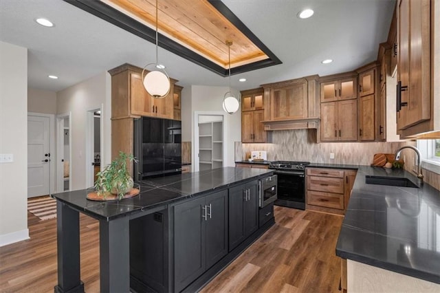 kitchen featuring dark wood-type flooring, a breakfast bar, sink, pendant lighting, and stainless steel appliances