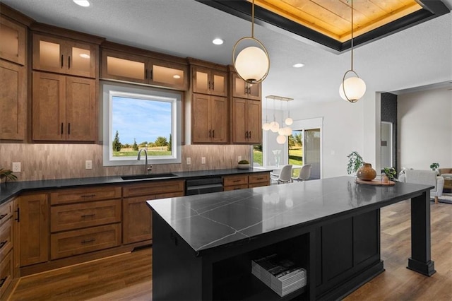 kitchen with decorative light fixtures, dishwasher, sink, a center island, and a tray ceiling