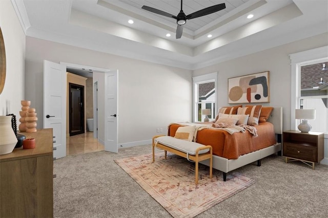 carpeted bedroom featuring ceiling fan and a tray ceiling