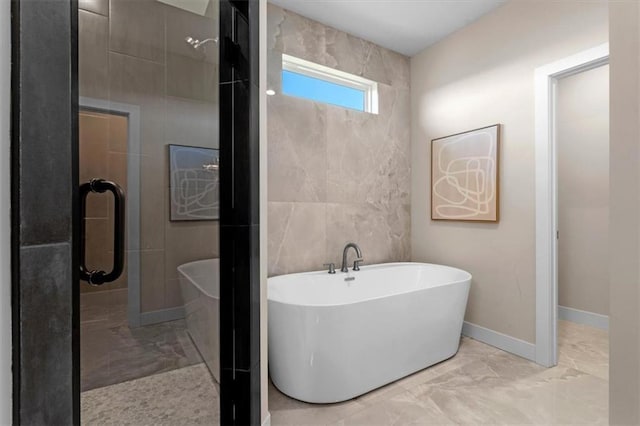 bathroom with shower with separate bathtub and tile walls