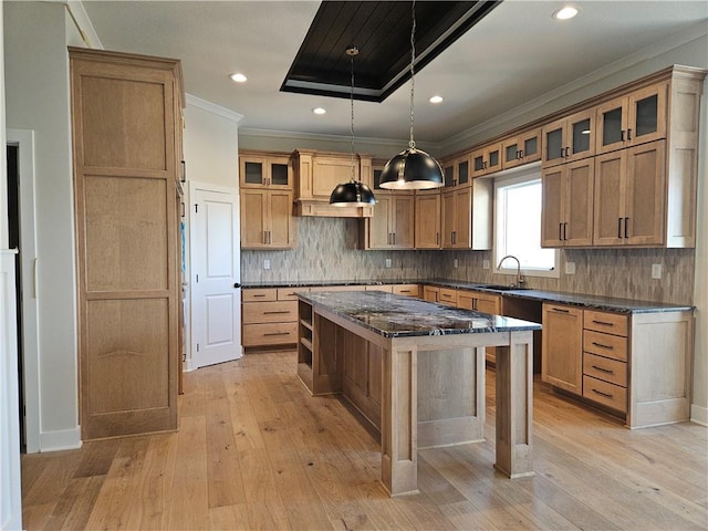 kitchen featuring a kitchen breakfast bar, ornamental molding, light hardwood / wood-style floors, a kitchen island, and decorative light fixtures