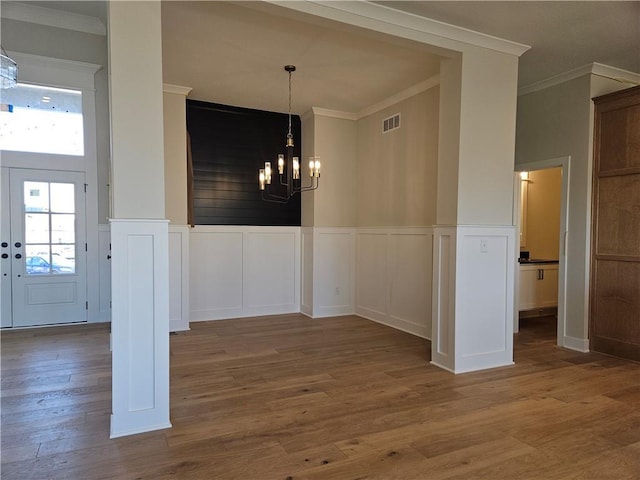 unfurnished dining area with a notable chandelier, crown molding, and dark wood-type flooring