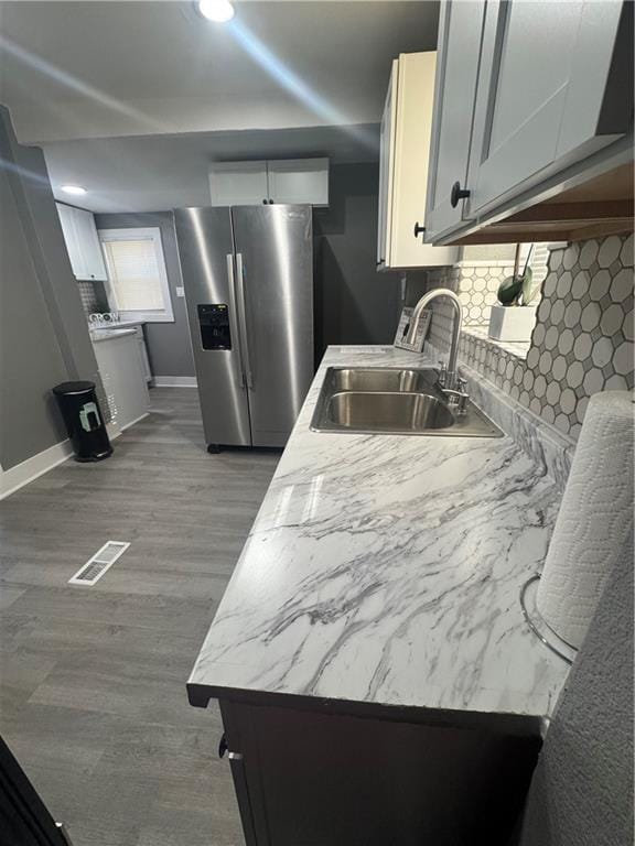 kitchen featuring white cabinetry, sink, wood-type flooring, and stainless steel refrigerator with ice dispenser