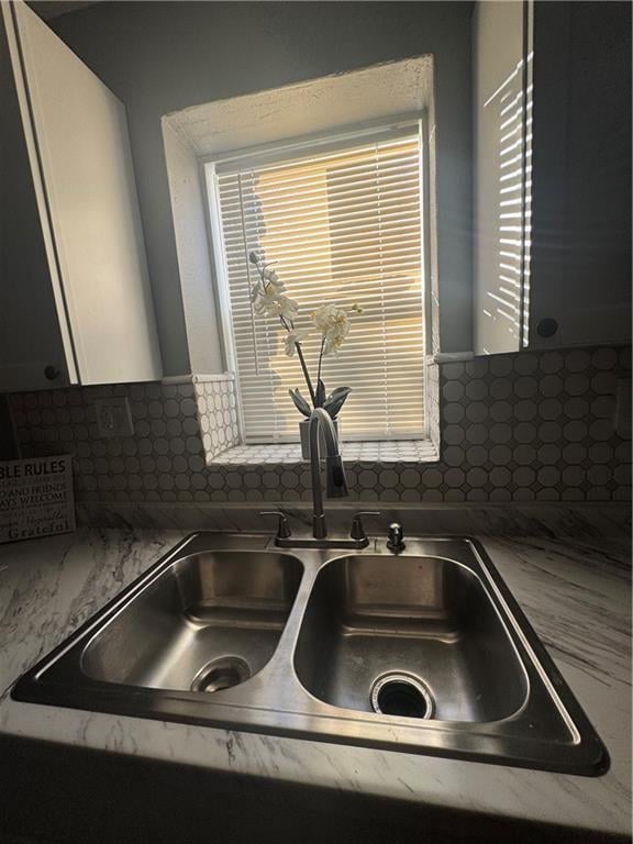 interior details with white cabinets, sink, and backsplash