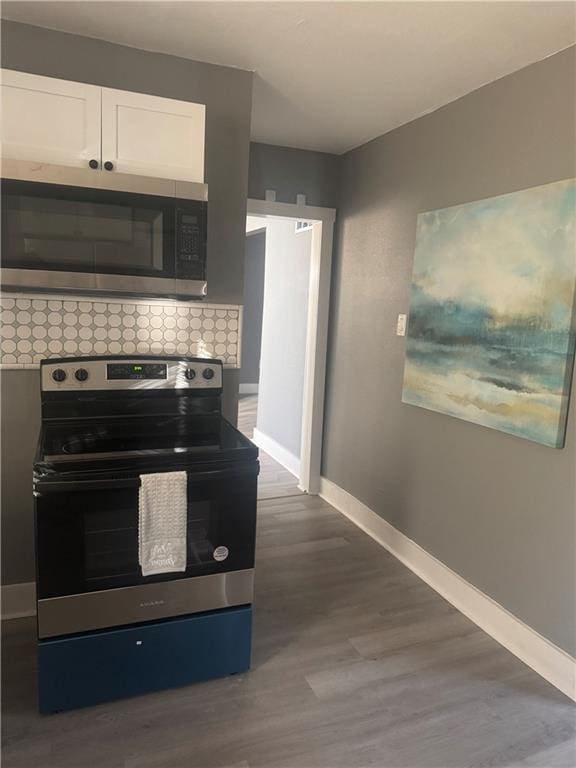 kitchen with white cabinets, dark wood-type flooring, appliances with stainless steel finishes, and tasteful backsplash