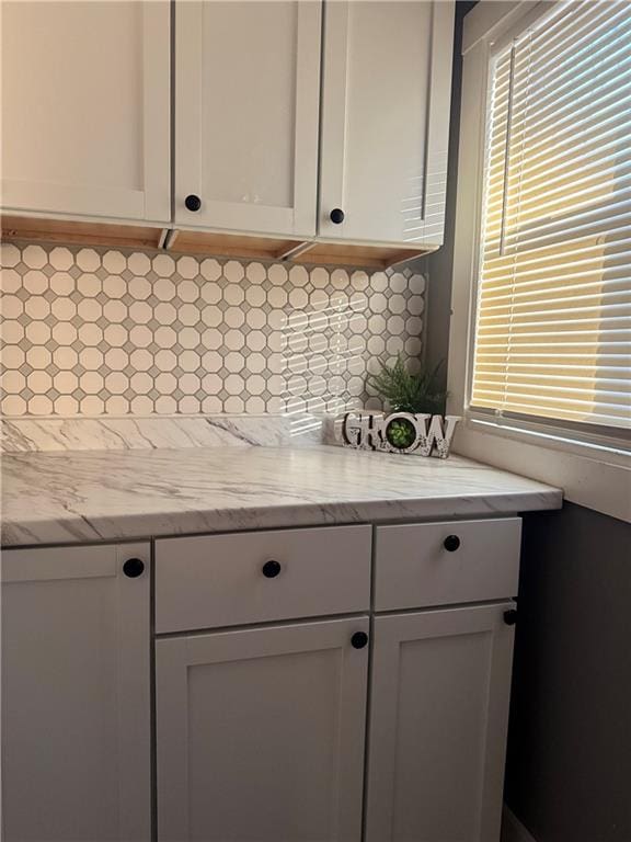 kitchen featuring white cabinets, decorative backsplash, and light stone counters