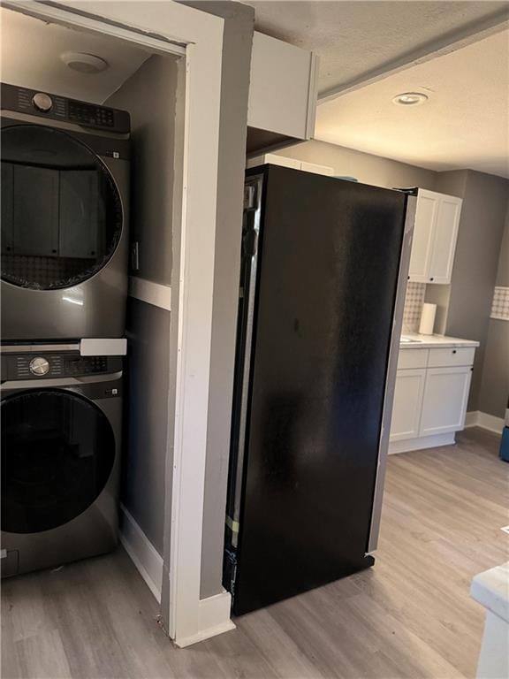 laundry area featuring light wood-type flooring and stacked washing maching and dryer