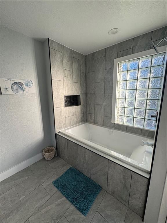 bathroom with tile patterned floors, a relaxing tiled tub, and a textured ceiling