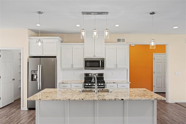 kitchen with appliances with stainless steel finishes, white cabinetry, and a kitchen island with sink