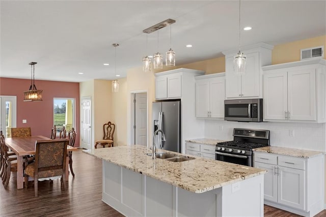 kitchen featuring pendant lighting, white cabinets, a center island with sink, sink, and appliances with stainless steel finishes