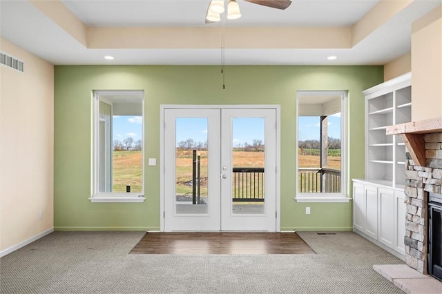 entryway featuring plenty of natural light, a stone fireplace, and light carpet