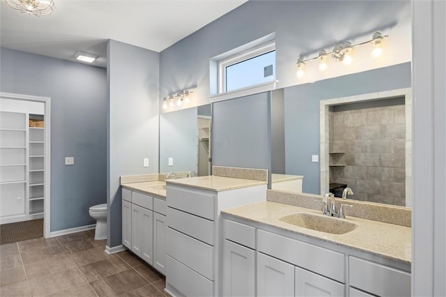 bathroom featuring tiled shower, vanity, toilet, and tile patterned flooring