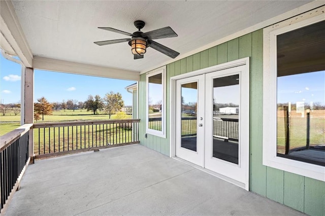 unfurnished sunroom featuring ceiling fan and french doors