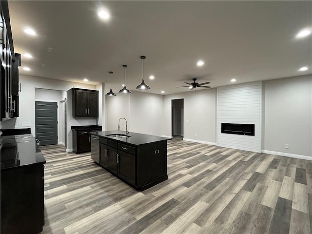 kitchen with a kitchen island with sink, sink, stainless steel dishwasher, ceiling fan, and light hardwood / wood-style flooring