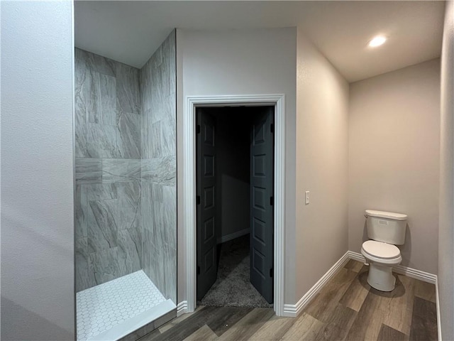 bathroom featuring tiled shower, wood-type flooring, and toilet