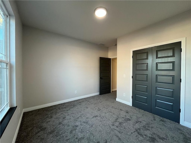 unfurnished bedroom with dark colored carpet and a closet