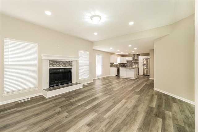 unfurnished living room with a tiled fireplace and dark hardwood / wood-style floors