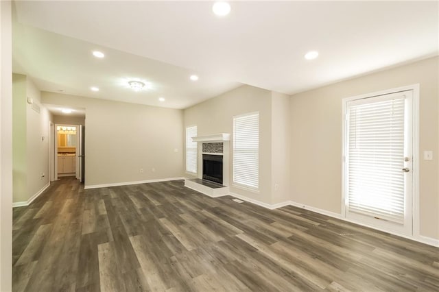 unfurnished living room with a wealth of natural light, dark hardwood / wood-style floors, and a fireplace