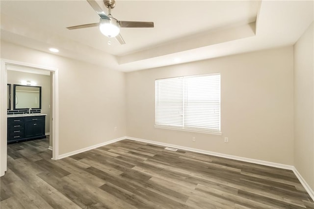 spare room with ceiling fan, dark hardwood / wood-style floors, a raised ceiling, and sink