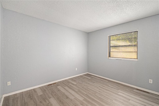 unfurnished room featuring a textured ceiling and light hardwood / wood-style floors