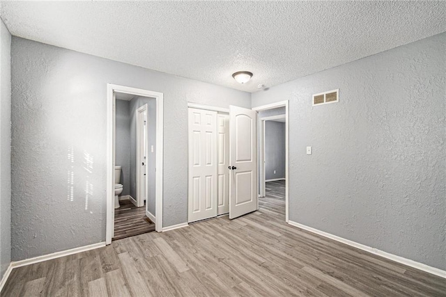 spare room with a textured ceiling and light hardwood / wood-style floors