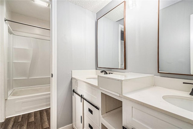 bathroom featuring a textured ceiling, shower / washtub combination, hardwood / wood-style flooring, and vanity