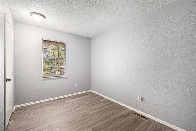 empty room with a textured ceiling and hardwood / wood-style flooring