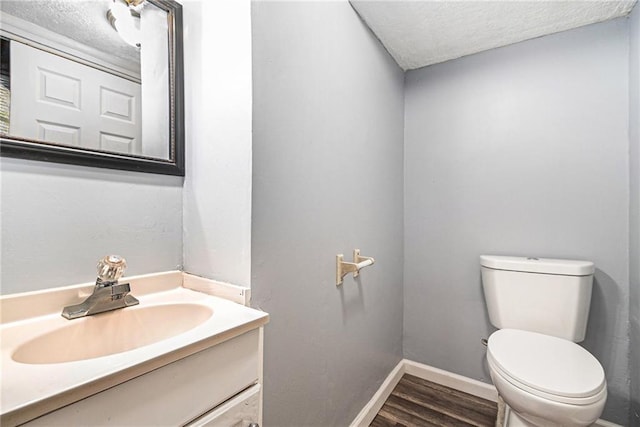 bathroom with wood-type flooring, a textured ceiling, toilet, and vanity