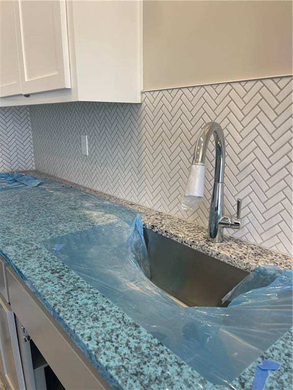 kitchen with white cabinetry, light stone counters, and decorative backsplash