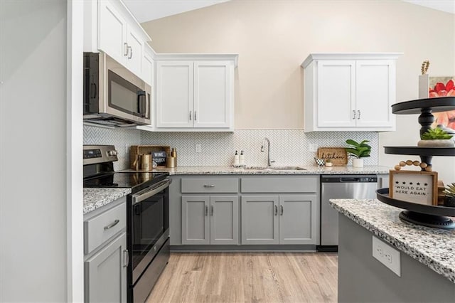kitchen with a sink, stainless steel appliances, tasteful backsplash, and gray cabinets