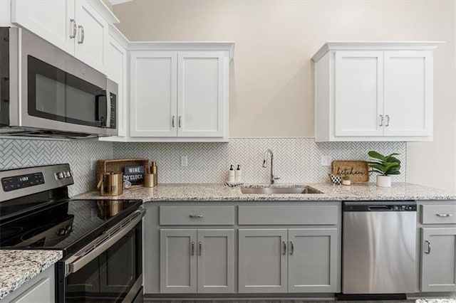 kitchen with a sink, gray cabinetry, decorative backsplash, and appliances with stainless steel finishes