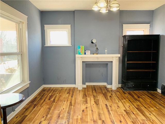 unfurnished living room featuring hardwood / wood-style floors, plenty of natural light, and a notable chandelier