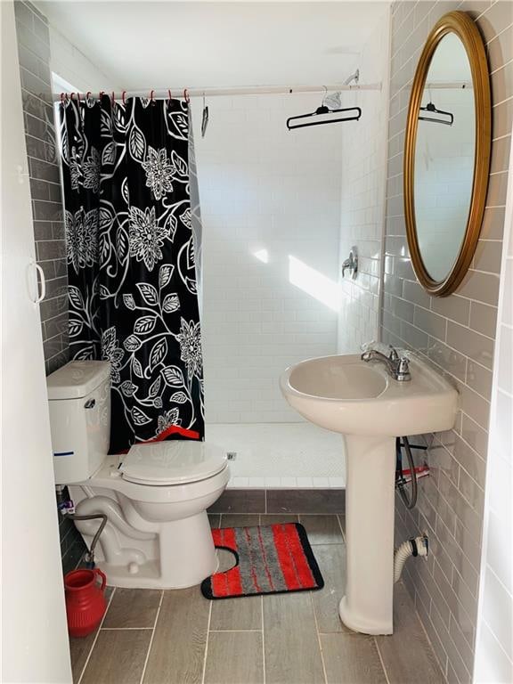 bathroom featuring tile walls, sink, toilet, and a shower with curtain