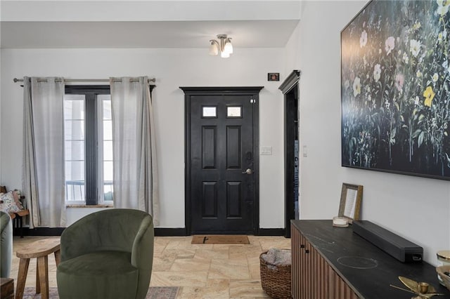 foyer entrance with stone finish flooring and baseboards