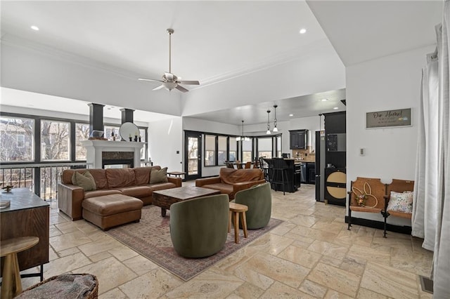 living area featuring ornamental molding, a fireplace, stone tile flooring, and recessed lighting