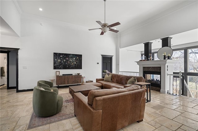 living area featuring ornamental molding, a towering ceiling, stone tile flooring, and baseboards