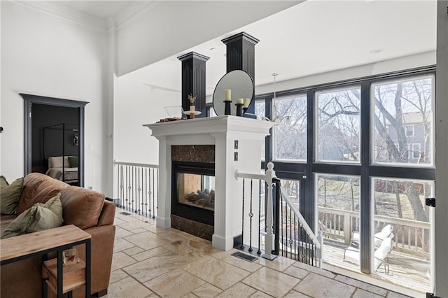 living room with stone tile floors, crown molding, and a multi sided fireplace