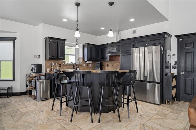 kitchen featuring freestanding refrigerator, backsplash, and a breakfast bar area