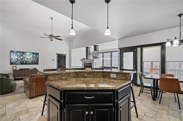 kitchen with ornamental molding, dark cabinetry, open floor plan, and a kitchen bar