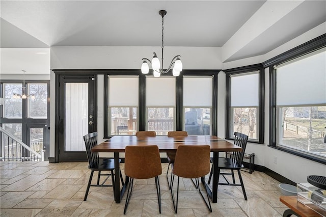 dining area featuring an inviting chandelier, stone tile floors, and baseboards