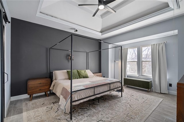 bedroom with ceiling fan, baseboards, a raised ceiling, and wood finished floors